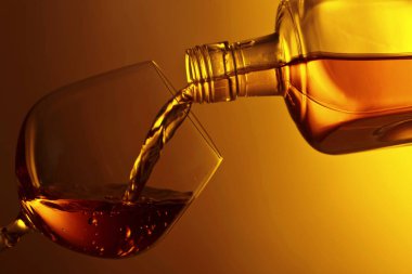 Glass filled with brandy from the bottle .Copy space for text. clipart