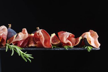 Prosciutto incir ve biberiye siyah bir arka plan ile.