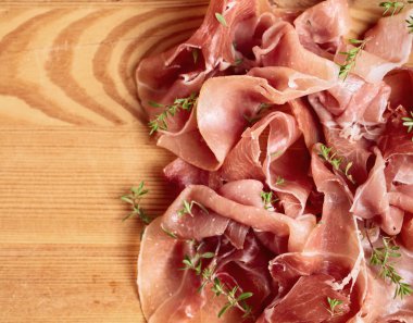 İtalyan prosciutto crudo veya jamon ahşap bir masa üzerine kekik ile. Üstten görünüm, metniniz için kopya alanı.