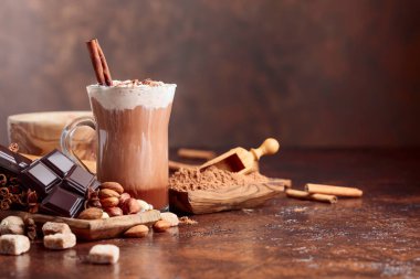 Kakao krema, tarçın, çikolata parçaları ve kahverengi bir arka plan üzerinde çeşitli baharatlar ile. Metniniz için kopya alanı.