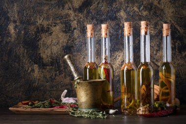 Şişe zeytinyağı eski ahşap bir masa üzerinde. Farklı baharatlar ve otlar ile zeytinyağı. Kopya alanı.