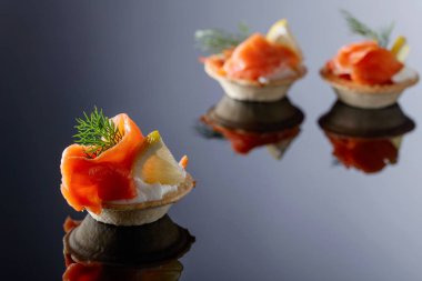 Somon balığı, krema ve bir dilim limon siyah bir arka plan ile tartlets.