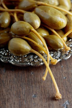 Metal tabak içinde turşu Kapari Karpuzu. Capparis yenilebilir meyve. Çilek garnitür olarak kullanılır. Eski ahşap arka plan.