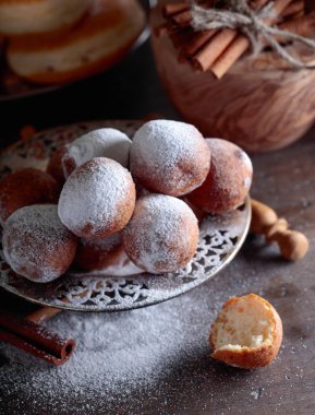 Eski ahşap bir masa üzerinde şekerle toz tarçın ile tatlı çörek.