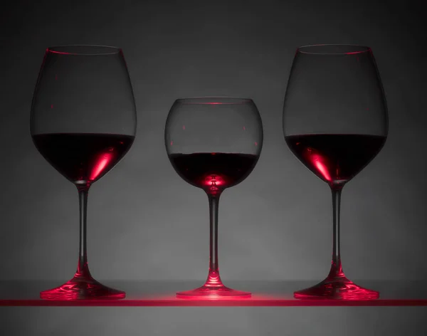 Glasses of red wine on a dark background.