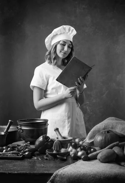 Mooi Meisje Een Chef Uniform Leest Een Oud Kookboek Tafel — Stockfoto