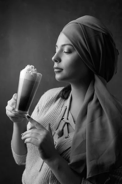 Young sexy beautiful woman in brown turban picked up holding a  mug  coffee with cream.  Perfect makeup, brown background.  Model plus size.