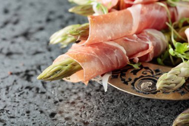 Prosciutto ile tere salatası gri metal arka plan üzerinde sarılı kuşkonmaz.