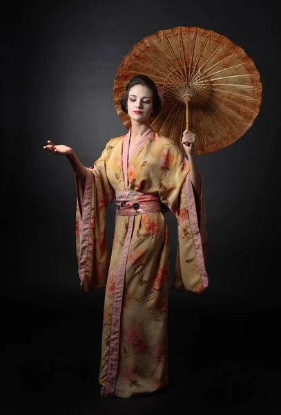 传统日本和服的年轻美女在黑色背景上带雨伞 — 图库照片