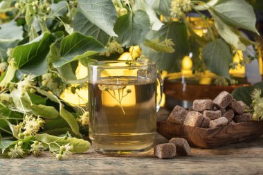 Bardak kahverengi şeker ve ahşap masaya çiçek ile Ihlamur Çayı.