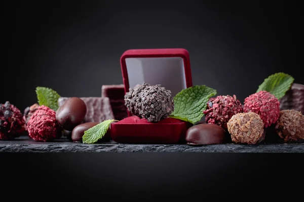 Various chocolates with mint leaves and a small gift box. Copy space.