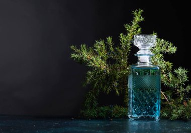 Mavi cin crystal sürahi ve ardıç daldaki meyveleri siyah bir arka plan ile. Metniniz için kopya alanı.