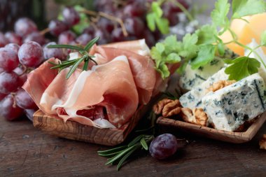 Çeşitli peynirler, üzüm ve prosciutto eski bir ahşap tablo.