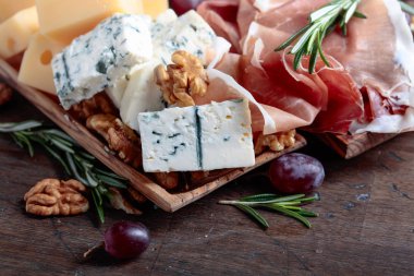 Prosciutto mavi peynir, üzüm ve eski ahşap bir masa üzerinde ceviz.