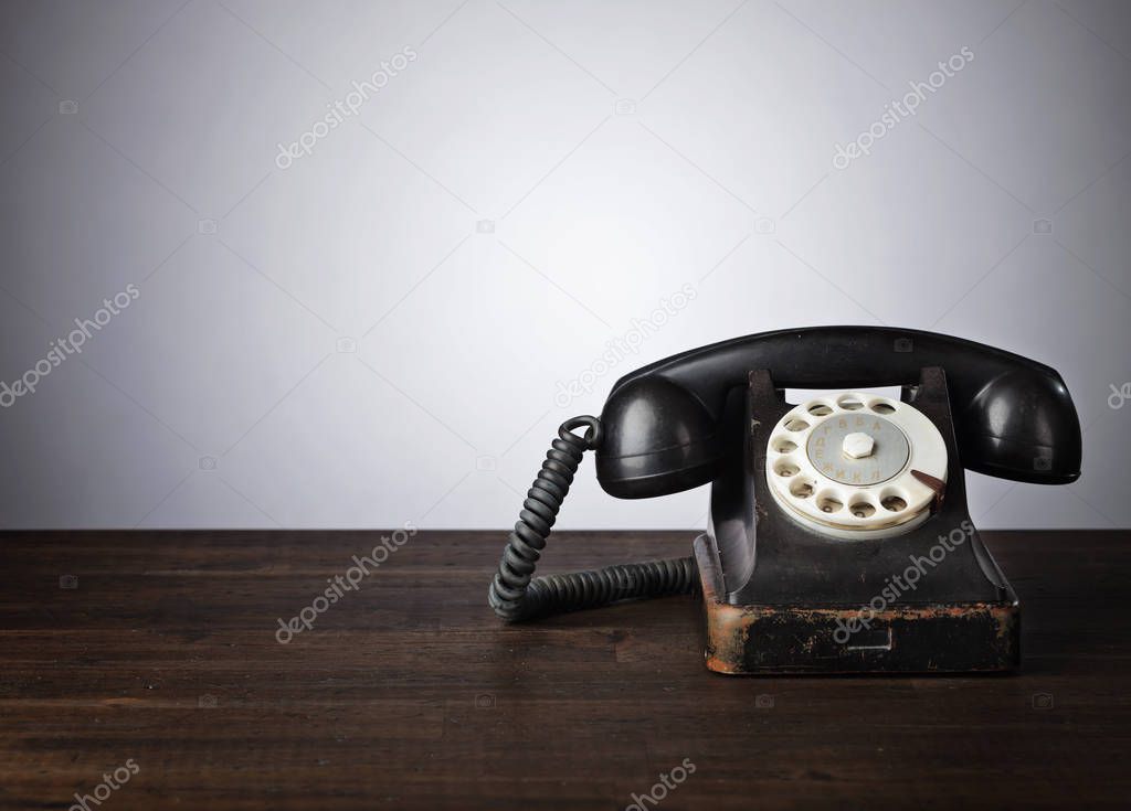 Old black phone on a wooden table. Copy space for your text .