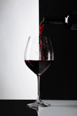 Červené víno se nalije do sklenice. Reflexivní pozadí, kopie místo pro váš text.