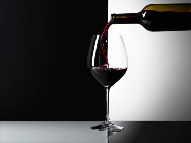 Kırmızı şarap bir bardak dökülür. Yansımalı arka plan, metniniz için kopya alanı.