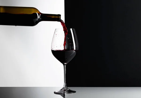 Red wine is poured into a glass. Reflexive background, copy space for your text.