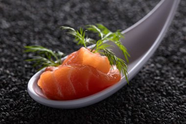 Siyah susam arka plan üzerine dereotu ile tuzlanmış somon dilim.