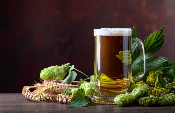 Mug of beer, grain and hops on a old wooden table. Free space for text.