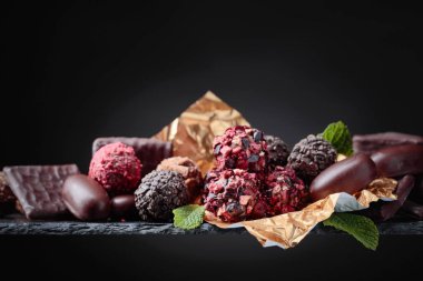 Siyah bir zemin üzerine altın folyo çeşitli çikolatalar. Metniniz için kopya alanı.