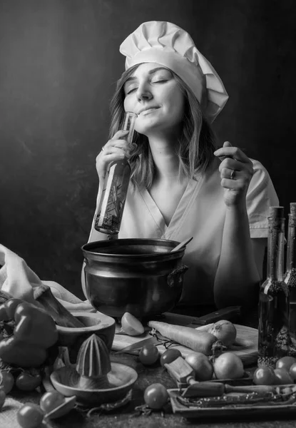 年轻漂亮的女孩在一个厨师制服与小瓶橄榄油 芳香橄榄油用各种各样的香料和草本 — 图库照片