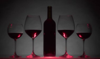 Gözlük ve karanlık bir arka plan üzerinde kırmızı şarap şişe.