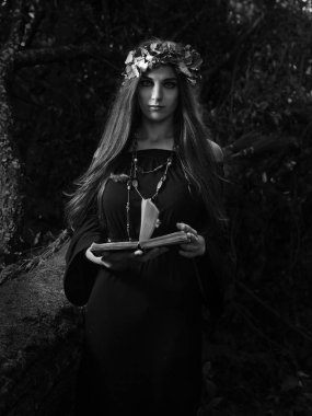 Vintage Gotik Giysi ve büyülü kitap tutan güzel genç halloween cadı. Karanlık ormanda cadı. Siyah ve beyaz.