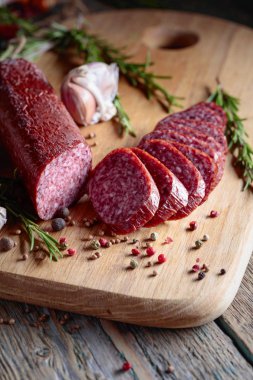 Eski ahşap bir masada tütsülenmiş salam. Biberiye, sarımsak ve biberli sosis..