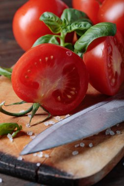 Ahşap masa zemin üzerine yeşil Fesleğenli kırmızı domates.