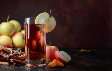 Bardak elma suyu veya elma suyu ile sulu elma ve tarçın bir mutfak masasında.