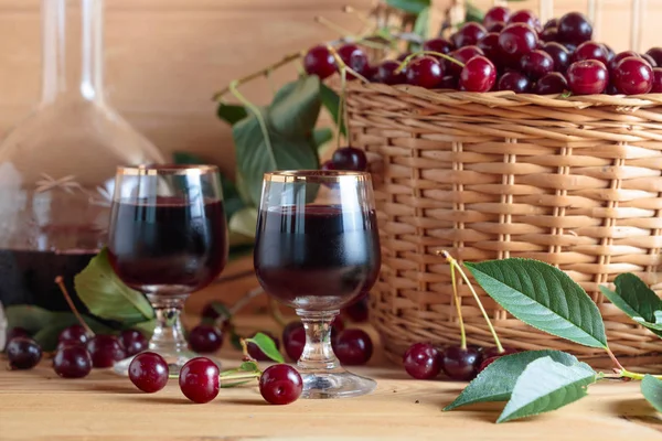 stock image Cherry wine or liquor on wooden background and ripe juicy cherries in basket.