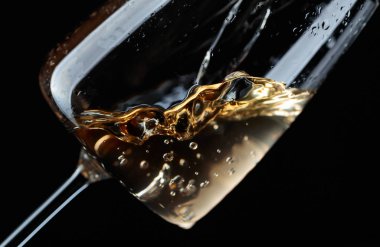 Beyaz şarap şarap cam içine siyah bir arka plan üzerine dökülür varlık.