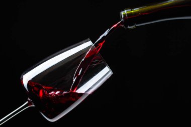 Kırmızı şarap şarap cam içine siyah bir arka plan üzerine dökülür varlık.