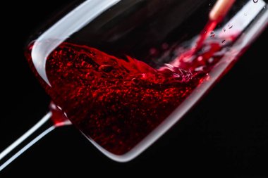 Kırmızı şarap şarap cam içine siyah bir arka plan üzerine dökülür varlık.