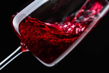 Kırmızı şarap şarap cam içine siyah bir arka plan üzerine dökülür varlık.