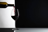 Červené víno se nalije do sklenice. Reflexivní pozadí, kopie místo pro váš text.
