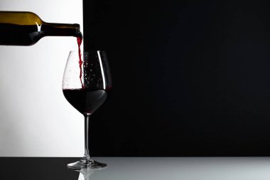 Kırmızı şarap bir bardak dökülür. Yansımalı arka plan, metniniz için kopya alanı.