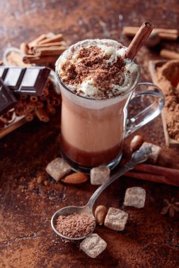Kakao krema, tarçın, çikolata parçaları ve kahverengi bir arka plan üzerinde çeşitli baharatlar ile. 