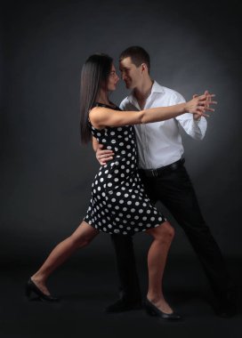 Puantiyeli elbise ve tango dans Beyaz tişörtlü adam genç güzel kadın. Kaç stüdyoda dans aşk içinde.