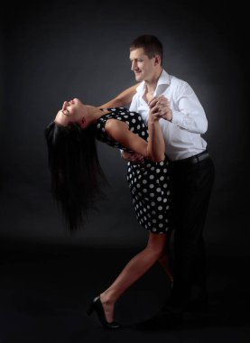 Puantiyeli elbise ve tango dans Beyaz tişörtlü adam genç güzel kadın. Kaç stüdyoda dans aşk içinde.