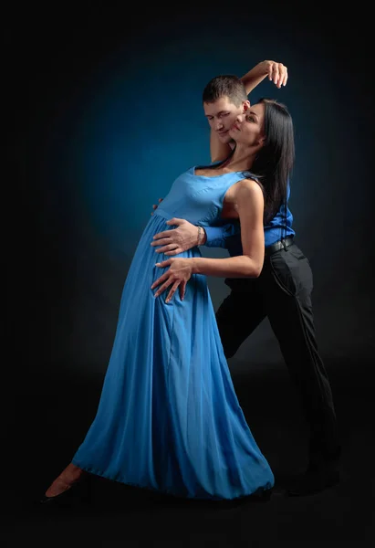 年轻美丽的女人在长蓝色礼服和男人在蓝色衬衫跳舞探戈 情侣在爱跳舞在演播室 — 图库照片