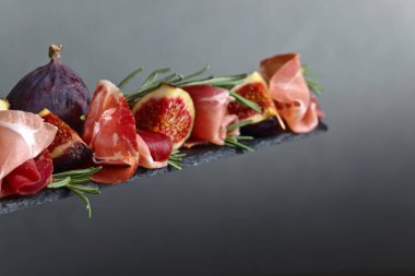 Prosciutto incir ve biberiye karanlık bir arka plan üzerinde.