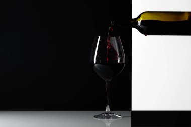 Kırmızı şarap bir bardak dökülür. Yansımalı arka plan, metniniz için kopya alanı.