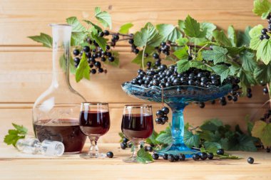 Ev yapımı siyah frenk üzümü likör ve dal, ahşap arka plan taze çilek.