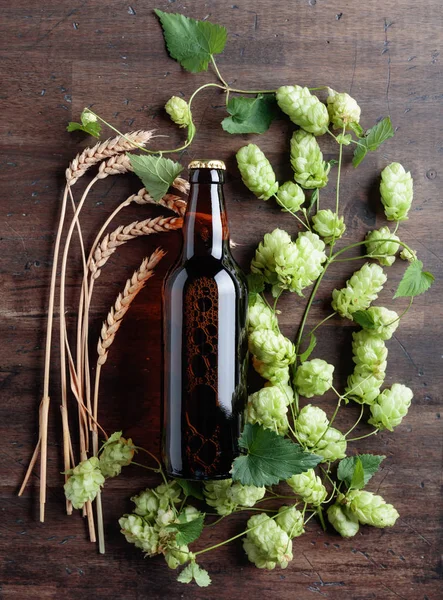 Bottle of beer, grain and hops on a old wooden background. Top view. Free space for text.