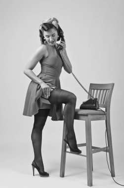 PIN tarzında vintage telefonla konuşan güzel esmer kadın. Çekici genç kadın 50s tarzı mükemmel makyaj ve saç modeli ile. Siyah ve beyaz.