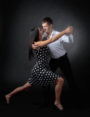 Puantiyeli elbise ve tango dans Beyaz tişörtlü adam genç güzel kadın. Kaç stüdyoda dans aşk içinde.