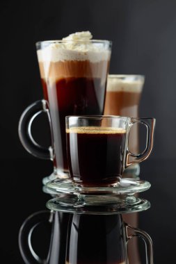 Siyah yansıtıcı arka planda çeşitli kahve içecekler.