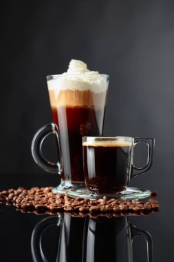 Siyah yansıtıcı arka planda çeşitli kahve içiyor. Espresso ve İrlandalı kahve Cam bardaklar.